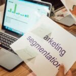 Analityk przy biurku przegląda dane marketingowe na laptopie i wydrukach