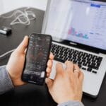Osoba analizuje dane afiliacyjne na smartfonie i laptopie