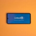Ekran logowania LinkedIn na smartfonie na pomarańczowym tle