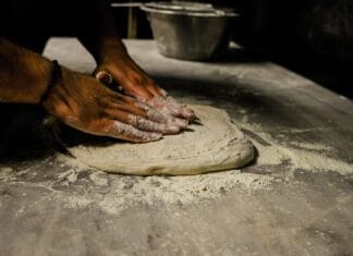 Jak przygotować idealne ciasto na domową pizzę: sprawdzony przepis krok po kroku Mężczyzna zagniata ciasto na pizzę na oprószonym mąką blacie