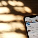 Smartfon z otwartym profilem LinkedIn na drewnianym stole