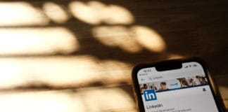 Smartfon z otwartym profilem LinkedIn na drewnianym stole